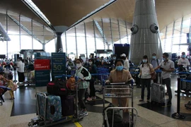 Các công dân Việt Nam từ Malaysia làm thủ tục lên máy bay để về nước ngày 5/7. (Ảnh: Hà Ngọc/TTXVN)