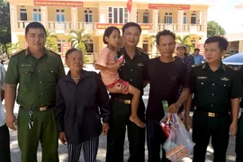 Lực lượng chức năng tỉnh Quảng Bình trao cháu Dương Thị Diễm Quỳnh cho gia đình. (Ảnh: Văn Tý/TTXVN)
