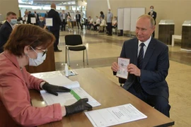 Tổng thống Nga Vladimir Putin (phải) làm thủ tục tại điểm bỏ phiếu trưng cầu dân ý về sửa đổi Hiến pháp ở Moskva ngày 1/7/2020. (Ảnh: AFP/TTXVN)