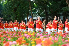 Người dân Thủ đô mặc đồng phục cờ Tổ quốc biểu diễn bài tập dưỡng sinh bên hồ Gươm sáng 2/9. (Ảnh: TTXVN)