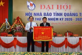Chủ tịch UBND tỉnh Quảng Trị Võ Văn Hưng trao tặng Cờ thi đua đơn vị dẫn đầu phong trào thi đua năm 2019 cho Hội Nhà báo tỉnh. (Ảnh: Hồ Cầu-TTXVN)