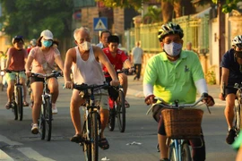 Người dân đeo khẩu trang tập thể dục sáng sớm trên phố Trích Sài, Tây Hồ. (Ảnh: Lâm Khánh/TTXVN)