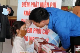 Phát miễn phí và hướng dẫn đeo khẩu trang đúng cách cho các em thiếu nhi. (Ảnh: Trần Lê Lâm/TTXVN)
