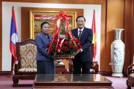 Bà Sounthone Sayachak trao lẵng hoa chúc mừng 90 năm ngày thành lập Đảng Cộng sản Việt Nam cho Đại sứ Việt Nam tại Lào Nguyễn Bá Hùng. (Ảnh: Phạm Kiên/Vietnam+)