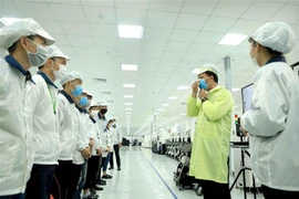 Công ty TNHH Compal Việt Nam trong khu công nghiệp Bá Thiện 1 (huyện Bình Xuyên) hướng dẫn cho công nhân đeo khẩu trang đúng cách để phòng dịch COVID-19. (Ảnh: Hoàng Hùng/TTXVN)