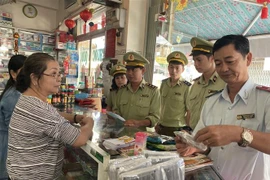 Lực lượng Quản lý thị trường tỉnh An Giang kiểm tra, nhắc nhở các hiệu thuốc tân dược ký cam kết không tăng giá bán khẩu trang y tế. (Ảnh: Công Mạo/TTXVN)