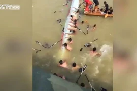 Những tay đua cố bám vào thuyền sau khi thuyền bị lật. (Nguồn: CCTV)