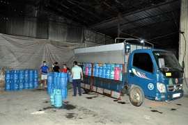 Lực lượng chức năng thu giữ phương tiện vận chuyển và nhiều bình gas đã được đóng niêm màng co, dán tem chuẩn bị đưa đi tiêu thụ. (Ảnh: TTXVN)