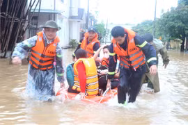 Lực lượng cứu nạn cứu hộ dùng xuồng di chuyển học sinh đến nơi an toàn. (Ảnh: Nguyên Lý/TTXVN)