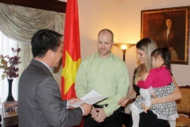 Đại sứ Việt Nam tại Canada Lê Sỹ Vương Hà trao quyết định về việc nhận con nuôi Việt Nam cho một gia đình ở Canada. (Ảnh: Thanh Hải/Vietnam+)