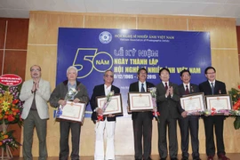 Thứ trưởng Bộ Văn hóa, Thể thao và Du lịch Vương Duy Biên trao kỷ niệm chương vì sự nghiệp Văn học Nghệ thuật cho các nghệ sỹ nhiếp ảnh. (Ảnh: Minh Đức/TTXVN)