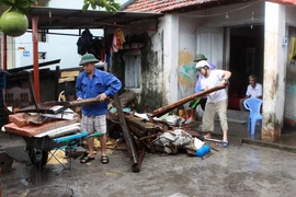 Người dân Cẩm Phả quét dọn nhà cửa lúc mưa ngớt. (Ảnh: Minh Quyết/TTXVN)