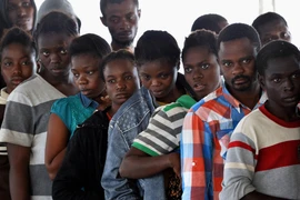 Người di cư xếp hàng nhận đồ ăn trên tàu Hải quân Đức sau khi được cứu vớt trên biển Địa Trung Hải ngày 27/9. (Nguồn: AFP/TTXVN)