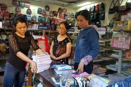 Phụ huynh mua sắm sách, đồ dùng học tập năm học mới cho con. (Ảnh: Thanh Thương/TTXVN)