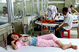 Bác sỹ Khoa Cấp cứu và chống độc, Bệnh viện sản nhi Cà Mau thăm khám, điều trị cho bệnh nhi mắc sốt xuất huyết nặng. (Ảnh: Kim Há/TTXVN)