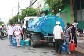 Người dân Rạch Giá phải sử dụng mọi vật dụng hiện có để lấy nước tại các xe bồn cấp nước. (Ảnh: Trường Giang/TTXVN)