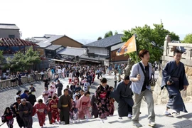 Hướng dẫn viên du lịch cầm cờ dẫn đầu đoàn du khách Trung Quốc mặc kimono thăm đền Kiyomizu-dera ở Kyodo. (Nguồn: Bloomberg)