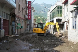 Công nhân dọn dẹp đường phố sau mưa bão phá hỏng ở thị trấn Sanpo, huyện Lai Thủy, tỉnh Hà Bắc, Trung Quốc. (Ảnh: THX/TTXVN)