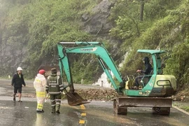 Lực lượng chức năng túc trực, xử lý các điểm bị sạt lở trên đèo Bảo Lộc, giúp các phương tiện lưu thông an toàn. (Ảnh: TTXVN phát)