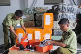 Cán bộ Đội Quản lý thị trường số 17 đang kiểm tra hàng hóa có dấu hiệu vi phạm sở hữu trí tuệ. (Ảnh: Đức Duy/Vietnam+)