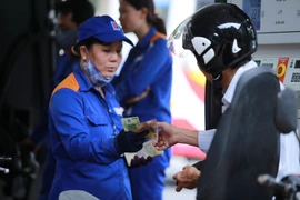 Nhân viên Petrolimex đang bán xăng cho khách hàng. (Ảnh: Đức Duy/Vietnam+)