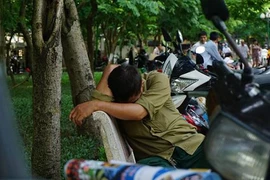 Một phụ huynh đến từ Quốc Oai, phải đi từ 5 giờ sáng nên anh có vẻ hơi mệt mỏi. (Ảnh: Võ Phương/Vietnam+)