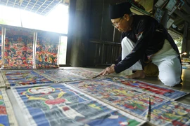 Ông Thanh thường xuyên phải kiểm tra, bảo quản những bức tranh thờ cổ của người Dao. (Ảnh: Nam Sương/TTXVN)