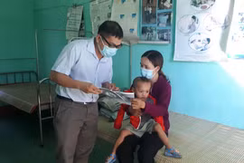 Cán bộ y tế địa phương phát tờ rơi tuyên truyền về bệnh bạch hầu để người dân phòng tránh. (Ảnh: Hồ Cầu/TTXVN)