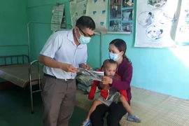 Cán bộ y tế địa phương phát tờ rơi tuyên truyền về bệnh bạch hầu để người dân phòng tránh. (Ảnh: Hồ Cầu/TTXVN)