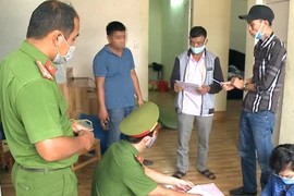 Cơ quan Công an đọc lệnh bắt đối tượng Trần Hữu Nguyễn Nhật Tân (đội mũ đen, ngoài cùng bên phải). (Ảnh: TTXVN)