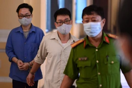 Bị cáo Lâm Hoàng Tùng (áo xanh), bị cáo Nguyễn Hải Nam (áo trắng) sau phiên tòa ngày 30/12/2020. (Ảnh: TTXVN phát)