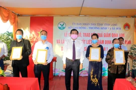 Phó Bí thư Thường trực Tỉnh ủy Vĩnh Long Bùi Văn Nghiêm trao kết quả giám định ADN xác định danh tính cho đại diện gia đình các liệt sỹ. (Ảnh: Lê Thúy Hằng/TTXVN)