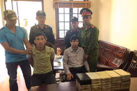 Hai đối tượng Hờ A Dà (trái), Phạm Minh Châu cùng tang vật 30 bánh heroin. (Ảnh: Xuân Tiến/TTXVN)