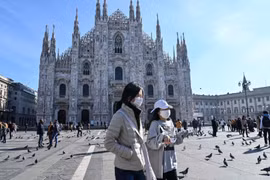 Người dân đeo khẩu trang phòng lây nhiễm dịch viêm đường hô hấp cấp COVID-19 ở Duomo, Milan, Italy ngày 24/2/2020. (Ảnh: AFP/TTXVN)