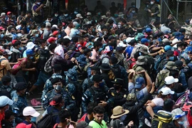 Người di cư Honduras phá hàng rào cảnh sát để vào Guatemala tìm đường tới Mỹ tại khu vực biên giới Corinto, Honduras, ngày 1/10/2020. (Ảnh: AFP/TTXVN)