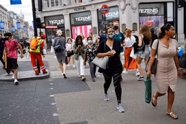 Người dân đeo khẩu trang phòng lây nhiễm COVID-19 khi di chuyển trên đường phố tại London. (Ảnh: AFP/TTXVN)