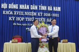 Ông Phạm Sỹ Lợi, Phó Bí thư thường trực Tỉnh ủy, Chủ tịch HĐND tỉnh Hà Nam tặng hoa chúc mừng ông Trần Xuân Dưỡng. (Ảnh: Thanh Tuấn/TTXVN)