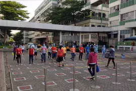 Công nhân Công ty TNHH Pouyuen Việt Nam thực hiện giãn ca, rửa tay khử trùng và đo thân nhiệt trước khi vào xưởng. (Ảnh: Thanh Vũ/TTXVN)