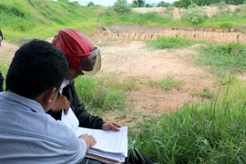 Cán bộ xã Bình Tân, huyện Bắc Bình kiểm tra biên bản vi phạm trồng trọt, xây dựng trên đất dự án cao tốc Bắc-Nam. (Ảnh: Nguyễn Thanh/TTXVN)