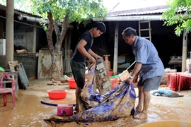 Ông Võ Văn Bình (bên phải), thôn Đồng Tư, xã Hiền Ninh, huyện Quảng Ninh (Quảng Bình) dọn dẹp nhà cửa sau lũ. (Ảnh: Văn Tý-TTXVN|)