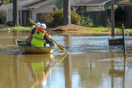 Nhân viên công ích di chuyển bằng thuyền để tắt điện trong những ngôi nhà bị ngập lụt ở Jackson, bang Mississippi.(Nguồn: nytimes.com)