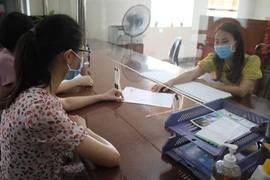 Nhân viên cục thuế tỉnh Ninh Bình hướng dẫn người dân làm thủ tục nộp thuế. (Ảnh: Hải Yến/TTXVN)