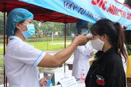 Thí sinh đo thân nhiệt trước khi vào phòng thi. Ảnh: Nguyễn Chiến. 