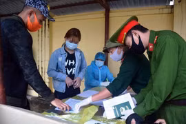 Các công dân ký giấy chứng nhận hoàn thành thời gian cách ly. (Ảnh: Phan Tuấn Anh/TTXVN)