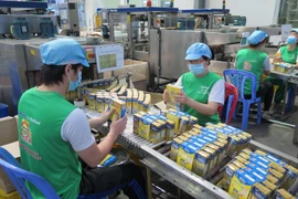 Kiểm tra và đóng gói sữa vào thùng tại nhà máy Nutifood Bình Dương (KCN Mỹ Phước I, Bến Cát). (Ảnh: Minh Hưng/TTXVN)