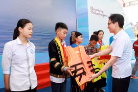 Phó Thủ tướng Vũ Đức Đam tặng áo phao cho đại diện các em học sinh các trường phải đi học qua sông. (Ảnh: PV/Vietnam+)