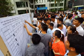 Người lao động xem danh sách thi tiếng Hàn để sang Hàn Quốc làm việc. (Ảnh: Hồng Kiều/Vietnam+)