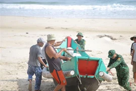 Lực lượng bộ đội biên phòng và người dân xã Giao Hải, huyện Gio Linh di chuyển các ghe, tàu có công suất từ 8-10 CV vào bờ tránh bão. (Ảnh: Thanh Thủy/TTXVN)