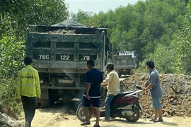 Một số đối tượng dùng xe tải chặn đầu, đổ đất bịt kín lối ra khỏi mỏ đất để uy hiếp phóng viên. (Ảnh: Lê Ngọc Phước/TTXVN)