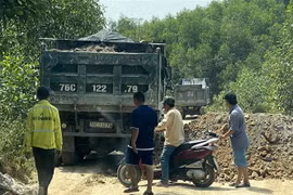 Một số đối tượng dùng xe tải chặn đầu, đổ đất bịt kín lối ra khỏi mỏ đất để uy hiếp phóng viên. (Ảnh: Lê Ngọc Phước/TTXVN)